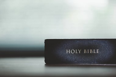 Tahta masanın üzerinde arka planda eğitim için kutsal İncil kitabı. Protestan inancı olan Hıristiyan Katolik kilisede dua ediyor. İnanç, Tanrı ve din hakkında bilgi edinme kavramı..