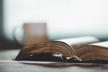 Tahta masanın üzerinde arka planda eğitim için kutsal İncil kitabı. Protestan inancı olan Hıristiyan Katolik kilisede dua ediyor. İnanç, Tanrı ve din hakkında bilgi edinme kavramı..