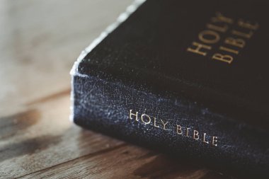 Tahta masanın üzerinde arka planda eğitim için kutsal İncil kitabı. Protestan inancı olan Hıristiyan Katolik kilisede dua ediyor. İnanç, Tanrı ve din hakkında bilgi edinme kavramı..