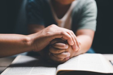 Hristiyan aile birlikte dua ediyor. Çocuk ve anne evde Tanrı 'ya tapıyor. Kadın ve çocuk elleri İncil 'le Tanrı' ya dua ediyor af diliyor ve iyiliğe inanıyor..