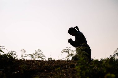 Diz çöküp beyaz arka planda Tanrı 'ya dua eden bir kadın silueti. Hıristiyanlar İsa 'ya sükunet için dua ediyorlar. Sabah insanlar sessiz bir yere gidip dua ettiler. Boşluğu kopyala.