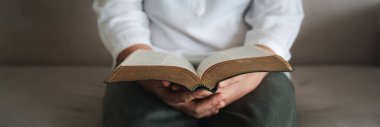 Kadın elleri İncil 'le Tanrı' ya dua ediyor. Onlar bağışlanma dilerler, iyiliğe inanırlar. Hristiyan hayatı, Tanrı 'ya dua etmek. Daha iyi bir hayat dilemek için Tanrı 'ya dua et. Kopyalama alanı olan pankart