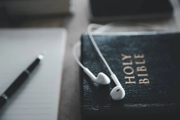 Stock image Christian online technology concept. Earphones over the holy bible with digital smartphone, Online live church for sunday service. Holy bible book and online study.