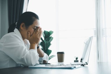Yorgun ve stresli genç bayan çalışan kişi ofiste ahşap masa üzerinde çalışıyor. Profesyonel iş kadını uykulu, aşırı çalışmaktan bunalımda. Çalışan kadın iş yerinde endişeli hissediyor..
