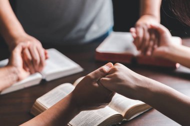 Hıristiyan grup dünya ve dünyanın dört bir yanındaki insanlar İncil 'le ahşap masada dua ediyor. Hıristiyan küçük bir grup el ele tutuşup İncil 'in olduğu ahşap bir masanın etrafında dua ediyor..