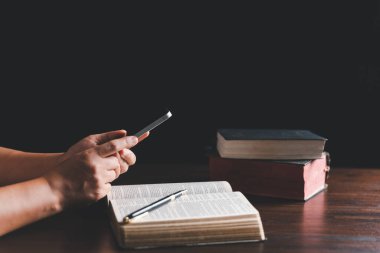 Christian online technology concept. Hands praying of christian with digital computer laptop, Online live church for sunday service. Asian catholic man are reading Holy bible book and online study.