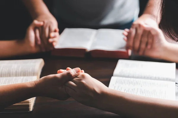 クリスチャングループは世界中の人々のために聖書と木製のテーブルの上で祈っています キリスト教の小グループが手を取り合い 家の教室に聖書のページがある木製のテーブルの周りで祈ります — ストック写真