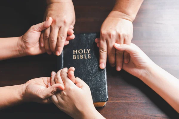 基督教团体用圣经在木制桌子上为全球和全世界的人祈祷 基督教小团体牵着手 在一张木制桌子周围祈祷 桌上有圣经页 — 图库照片