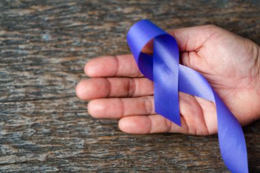 Koyu gri kırsal ahşap yüzeyde kadınlara uygulanan şiddetin kabul edilemez olduğunun farkındalığı için mor kurdele. Metin için boşluk olan üst görünüm. Aile içi şiddet farkındalığı.