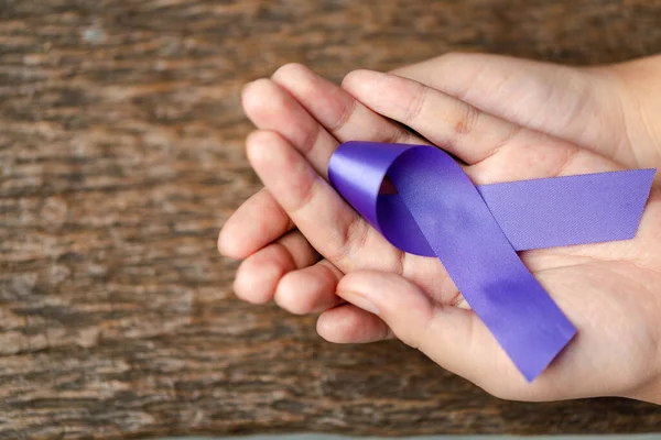 stock image Purple ribbon for the awareness about the unacceptability of the violence against women on dark gray rustic wooden surface. Top view with space for text. Domestic violence awareness.