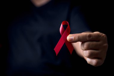 Siyah tişörtteki kırmızı kurdele. Bir insanın gömleğinde kurdele vardır. Kurdele HIV 'i önleme gününün sembolü. Farkındalık eğitimi açılış töreninde bir sürü kırmızı kurdele olacak..