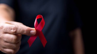 Siyah tişörtteki kırmızı kurdele. Bir insanın gömleğinde kurdele vardır. Kurdele HIV 'i önleme gününün sembolü. Farkındalık eğitimi açılış töreninde bir sürü kırmızı kurdele olacak..