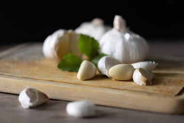 Lezzetli ev yemekleri için baharatlı sarımsak ve otlar. Taze sarımsak ve çeşitli aromatik otlar ahşap bir masada güzelce yerleştirilmiş, doğal aromaları ve kokuları çağrıştırıyor..
