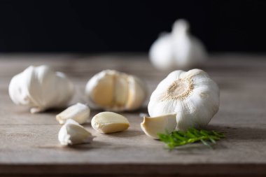 Lezzetli ev yemekleri için baharatlı sarımsak ve otlar. Taze sarımsak ve çeşitli aromatik otlar ahşap bir masada güzelce yerleştirilmiş, doğal aromaları ve kokuları çağrıştırıyor..