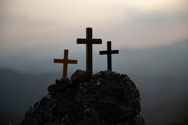 耶稣基督的三个神圣的十字架在红天 乌云和明亮的背景中闪烁着光芒 在加略山脉日落背景上的轮廓交叉 复活节概念 — 图库照片