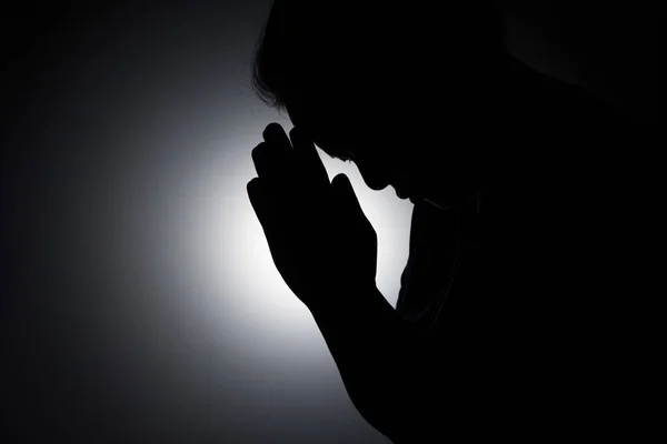 Profile silhouette of girl, young woman lowered her head and praying to God. Female catholic prayer worship to God wish a better life in home at dawn with believe faith.