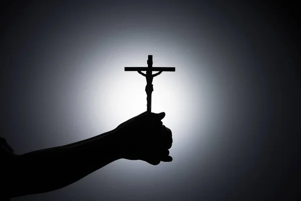 十字架を握り 十字架を閉じ 宇宙背景をコピーする暗黒の宗教的キリスト教のシンボルで神を祈る — ストック写真