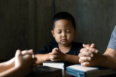 Hristiyan aile birlikte dua ediyor. Çocuk ve anne evde Tanrı 'ya tapıyor. Kadın ve çocuk elleri İncil 'le Tanrı' ya dua ediyor af diliyor ve iyiliğe inanıyor..