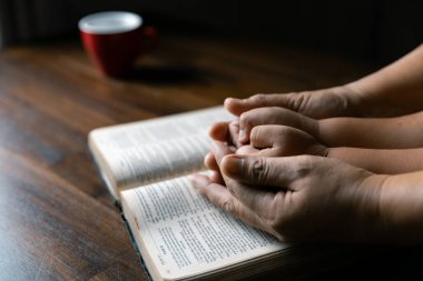 Hristiyan aile birlikte dua ediyor. Çocuk ve anne evde Tanrı 'ya tapıyor. Kadın ve çocuk elleri İncil 'le Tanrı' ya dua ediyor af diliyor ve iyiliğe inanıyor..