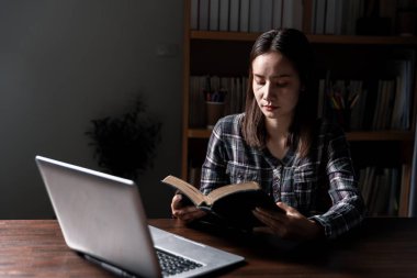 Hristiyan online teknoloji konsepti. Bilgisayarlı Christian 'a dua eden eller, pazar ayini için canlı kilise. Asyalı katolik adam kutsal kitap ve online çalışma okuyor..