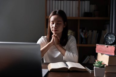 Hristiyan online teknoloji konsepti. Bilgisayarlı Christian 'a dua eden eller, pazar ayini için canlı kilise. Asyalı katolik adam kutsal kitap ve online çalışma okuyor..