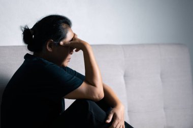 Çalışacak yaşa gelmiş yorgun ve stresli genç bir kadın evin oturma odasında çalışıyor.