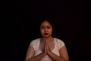 Gece karanlığında mum ışığında dua eden genç bir kız. Kadın kişi Tanrı 'ya inanç ve inançla tapar. Din, Hıristiyan dua kavramı. Hristiyan genç kız ve inanç.