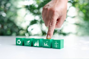 Elle bokeh doğa üzerine sıfır ikon ve beyaz simge içeren yeşil tahta küpleri yerleştirdim. Ağ sıfır ve karbon nötr konsept. Net sıfır sera gazı emisyon hedefi. İklim tarafsız uzun vadeli stratejisi.