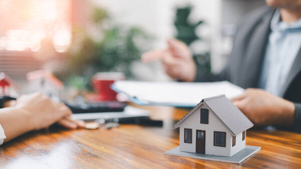 Real estate broker agent presenting and consult to customer to decision making sign insurance form agreement, home model, concerning mortgage loan offer in office. real estate agents about renting