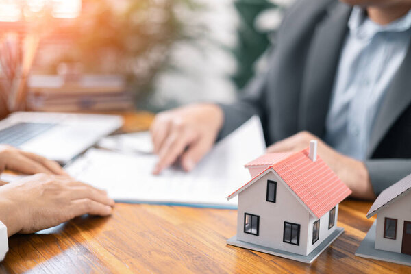 Real estate broker agent presenting and consult to customer to decision making sign insurance form agreement, home model, concerning mortgage loan offer in office. real estate agents about renting