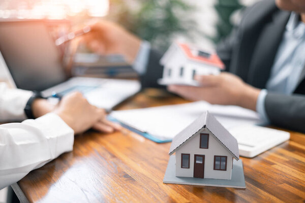 Real estate broker agent presenting and consult to customer to decision making sign insurance form agreement, home model, concerning mortgage loan offer in office. real estate agents about renting