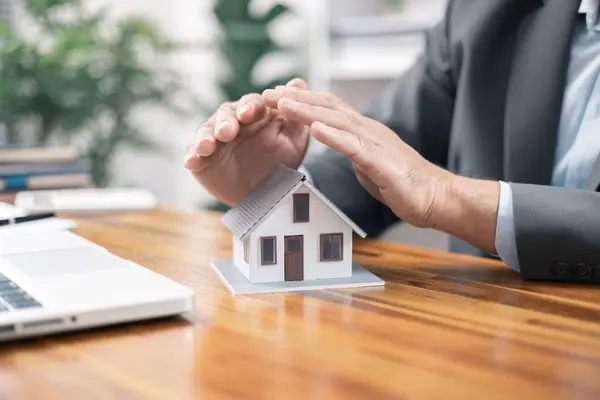 Insurance house concept. The insurance agent presents the hands protection model house. Make a contract for hire purchase and sale of a house. home insurance contracts, home mortgage loan concepts.