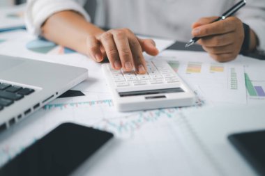 Muhasebe bankacılığı konsepti. Finans işleriyle ilgilenen bir iş kadını ve ofis masraflarını hesaplayan bir masa. Hesap makinesi ve mali muhasebe kullanan bir kadın..