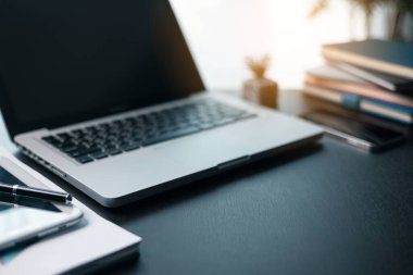 Bilgisayarı ve ahşap masasında akıllı telefonu olan bir ofis işyeri. Çalışma alanı, masaüstü bilgisayarı, ofis malzemeleri, ev bitkisi ve ofis kitapları. Masa başı işi konsepti. Bilgisayarda rahat çalışma masası.