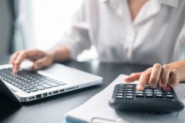 Resepsiyonda çalışan iş kadını hesap makinesi kullanarak rakamları hesaplıyor, muhasebe kavramını finanse ediyor. Kadın muhasebeci hesap makinesi ve bilgisayar kullanıyor. vergi, muhasebe, istatistik