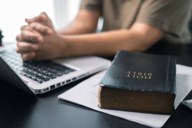 Hristiyan online din teknolojisi konsepti. Bilgisayarlı Christian 'a dua eden eller, pazar ayini için canlı kilise. Bilgisayar laptopuyla karanlıkta dua eden Asyalı kadın..