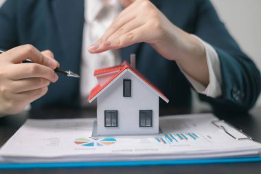 Ev sahibi mallarını sigorta acentesinin eline emanet etti. Evlerini ve maliyelerini bir ipotek sigortası planıyla güvence altına aldı. Ev sigortası kavramı.