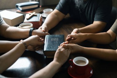 Hıristiyan kadın, dua ederken grupla el ele tutuşurken İncil 'ini sıkı sıkı tuttu. İnançları onları dini bir bağ ile birleştirdi. Hıristiyan grup dua kavramı.