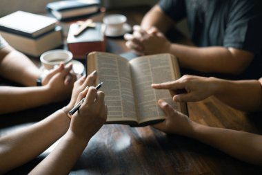 Hıristiyan kadın, dua ederken grupla el ele tutuşurken İncil 'ini sıkı sıkı tuttu. İnançları onları dini bir bağ ile birleştirdi. Hıristiyan grup dua kavramı.