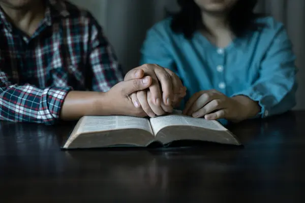 Hands clasped in prayer, Christians express their faith in God and worship Jesus Christ in the church, finding guidance and solace in the teachings of the Bible and their religious beliefs.