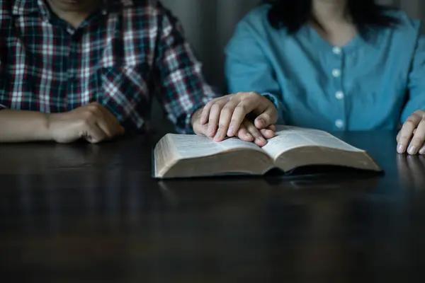 Hands clasped in prayer, Christians express their faith in God and worship Jesus Christ in the church, finding guidance and solace in the teachings of the Bible and their religious beliefs.