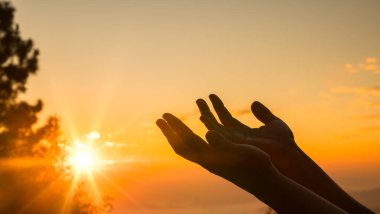 Gün doğumunda, dua eden bir Hıristiyan 'ın silueti, ibadet eden eller, inançlarını ve övgülerini yansıtarak, doğanın güzelliğinde huzuru buldu. İbadet, el, övgü, gündoğumu, dua, doğa.