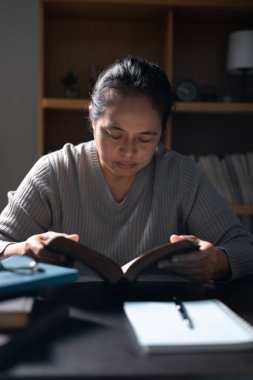 İncil 'i elinde tutan kadın, Tanrı' ya olan inancı kutsal kitaplarla güçlendi, teselliyi ve ilhamı Hristiyan dininde buldu. İncil, kadın, kitap, din, Hıristiyan, kutsal.