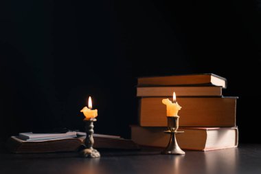 Karanlık, antik bir mum ışığını eski İncil 'e tutar alevleri masanın üzerindeki kitabın üzerinde hafifçe yanıp sönerek dinin kalıcı özünü sembolize eder. mum, İncil, karanlık, aydınlık, kitap, eski.