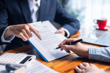 İş kadını mortgage belgesini gözden geçirirken ve müşterileriyle sözleşme imzalarken, kredi ve kredi detaylarını kesinleştirirken, emlak sigortası ve diğer finans yönlerini de tartıştı. finans, kredi, ödeme.