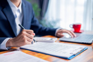 Adam müşterisiyle finans anlaşmalarını ve sözleşme belgelerini dikkatle gözden geçirdi, kredi, mortgage, yatırım fırsatları, kredi şartları ve işleri için vergi etkilerini tartıştı.