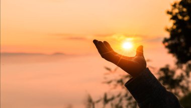Hristiyan kadın, Tanrı 'ya ibadet etmek ve dua etmek için elini kaldırdı. Huzurlu bir gündoğumu sabahı boyunca İsa Mesih aracılığıyla huzur bulmak için. İbadet, Hıristiyan, İsa Mesih, el, Tanrı, barış, dua, gün doğumu.