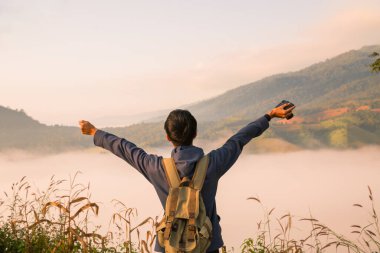 Gündoğumunda, tatilci, sis kaplı dağlarda yürüyüşün maceraperest yaşam tarzını benimsedi. Sırt çantası temel ihtiyaçlarla doluydu ve doğanın güzelliğine derin bir şükran duyuyordu. seyahat, gün doğumu, sis.