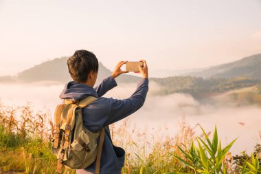 Gündoğumunda, tatilci, sis kaplı dağlarda yürüyüşün maceraperest yaşam tarzını benimsedi. Sırt çantası temel ihtiyaçlarla doluydu ve doğanın güzelliğine derin bir şükran duyuyordu. seyahat, gün doğumu, sis.