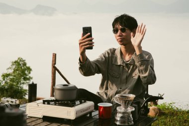 Peak Hill 'de bilgisayarda çalışan genç bir iş adamı. Günbatımında dizüstü bilgisayardan alışveriş yapan gezgin, dağın tepesinde gün doğumu yapan, dijital tabletle uzaktan kumandalı serbest çalışan biri. seyahat tatili konsepti